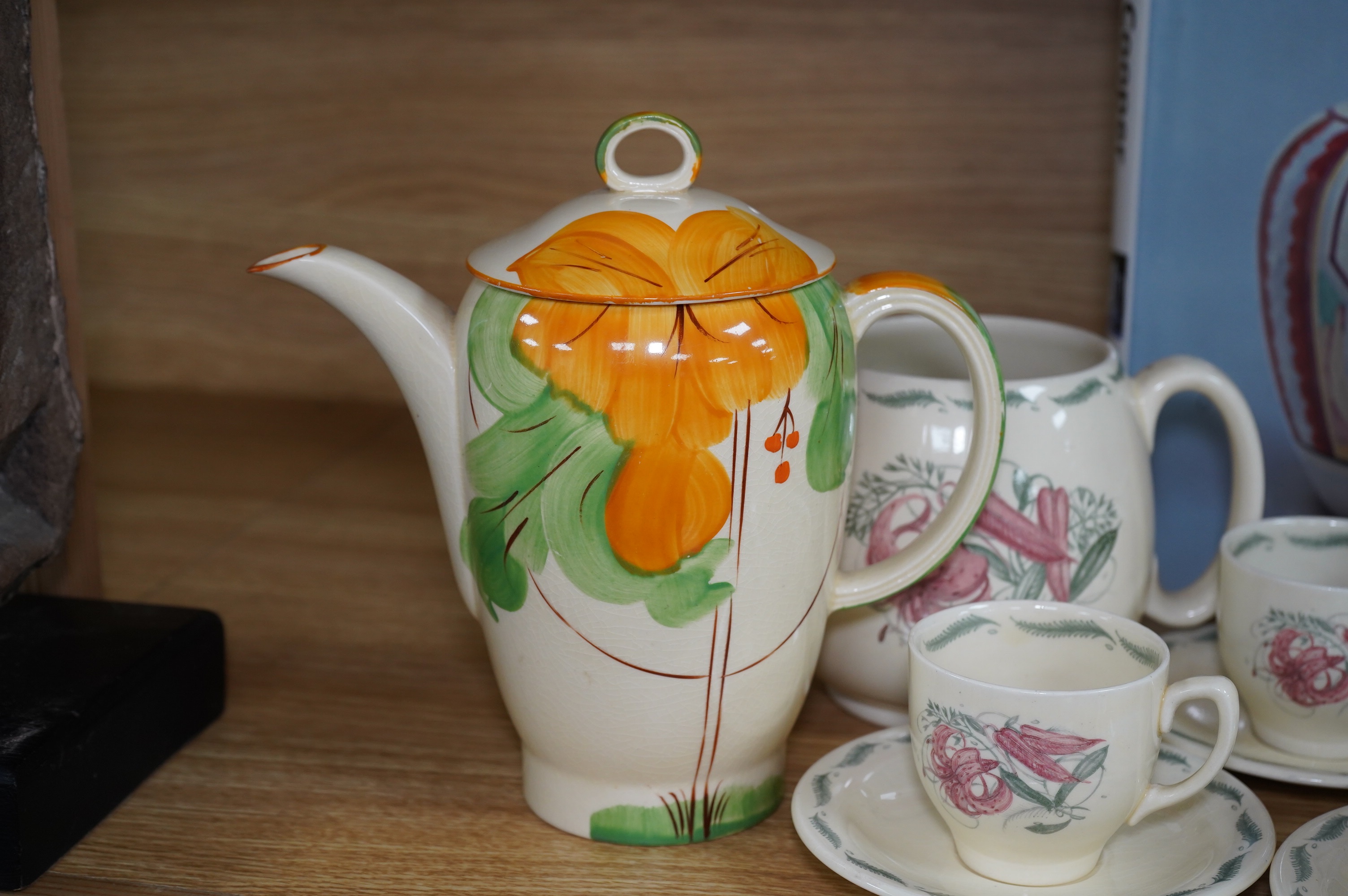 A Susie Cooper style 'Tiger Lily' pattern teaset, possibly by Wood & Co., a Susie Cooper reference book and a later painted Falcon shape coffee pot. Condition - good